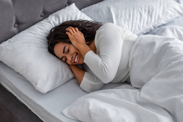 Černá žena pláče, leží v posteli a zakrývá obličej - Fotografie, Obrázek