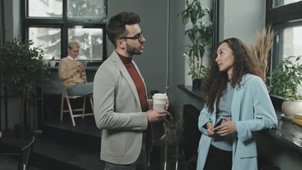 Medium traagheid van een paar collega 's staan in moderne coworking office met een gesprek - Video
