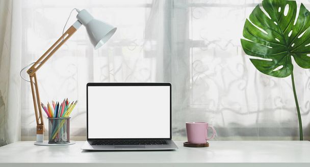 Comodo spazio di lavoro è circostante da un computer portatile bianco schermo bianco e varie attrezzature. - Foto, immagini