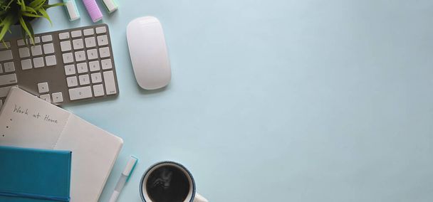 Top view image of wireless keyboard and mouse putting on orderly working desk that surrounded by note, marker pens, coffee cup, potted plant and pen. Orderly workspace concept. - Photo, Image