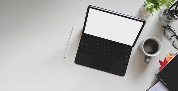 Tableta blanca de la pantalla en blanco con un lápiz de aguja está poniendo en un espacio de trabajo blanco con vista superior. - Foto, Imagen