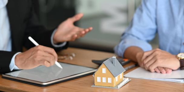 Image recadrée de l'agent immobilier offre une assurance habitation ou la propriété de la maison à l'homme intelligent en shir bleu - Photo, image