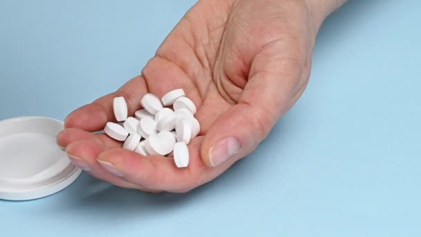 fehér kerek tabletták öntsük egy nő kezét, kék háttér - Felvétel, videó