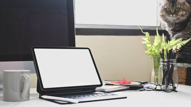 Una tableta de computadora con una caja de teclado está poniendo en un escritorio blanco en la oficina en casa. - Foto, imagen