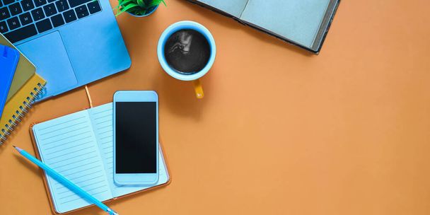 Bovenaanzicht afbeelding van bijgesneden witte smartphone met zwart leeg scherm zetten op kleurrijke bureau met koffiebeker, notitie, potlood, potplant en notebook. Kleurrijk werkruimteconcept. - Foto, afbeelding