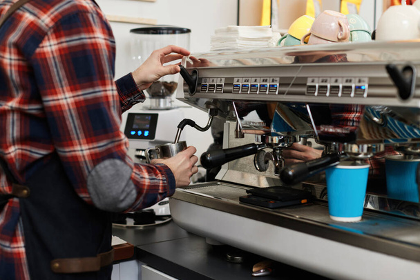 barista in apron pours fresh coffee into a cup - Фото, зображення