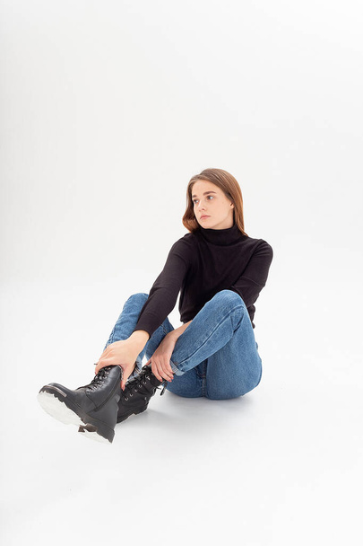 young attractive caucasian woman in black turtleneck, blue jeans at white studio - Photo, Image
