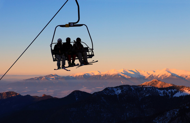 Hiihtohissi hiihtäjien kanssa sinisellä taivaalla illalla
 - Valokuva, kuva