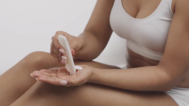 Gros plan de la jeune femme afro-américaine appliquant de la lotion sur la main avant les procédures de soins du corps, au ralenti - Séquence, vidéo