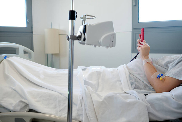 Terhes nő csepegtető a kórházban használja az okostelefonját - Fotó, kép
