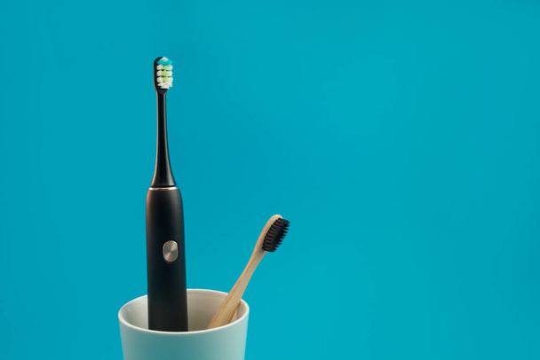 Ηλεκτρική οδοντόβουρτσα σε ποτήρι σε μπλε φόντο - Φωτογραφία, εικόνα