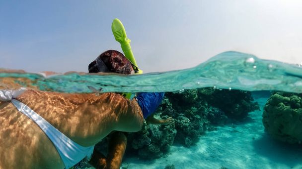 Letní dovolená šnorchlování v oceánu u potápěčského útesu. Maskovaný turista se dívá na písčité dno pod vodou. Podvodní rozdělené fotografie - Fotografie, Obrázek