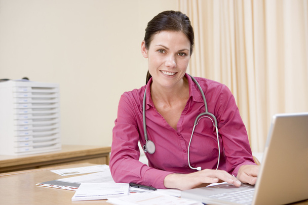 Médico usando laptop no escritório do médico sorrindo
 - Foto, Imagem