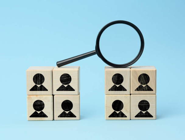 wooden cubes with staff black magnifier on blue background. Recruitment concept, search for talented and capable employees, career growth - Photo, Image