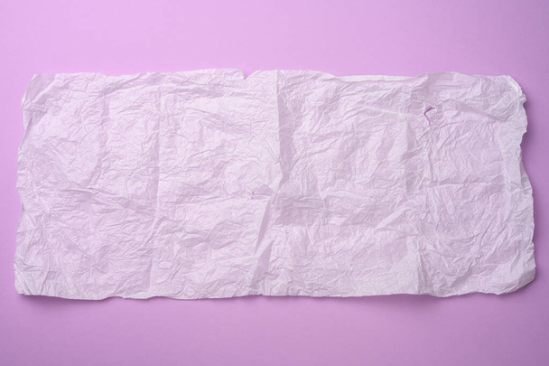 hoja de papel arrugada rectangular en tejido sobre un fondo púrpura, espacio de copia - Foto, imagen