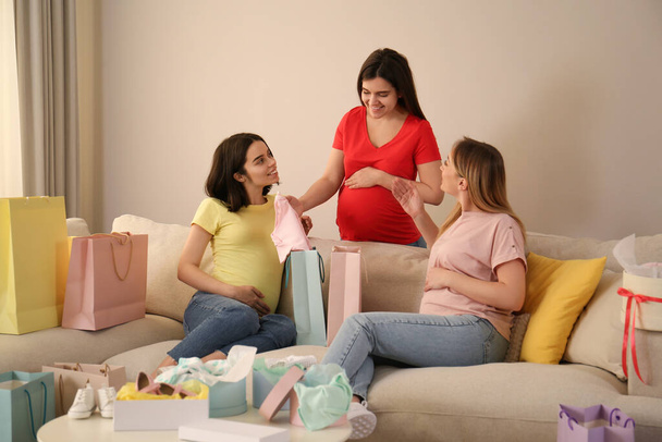 Happy pregnant women spending time together in living room after shopping - Zdjęcie, obraz