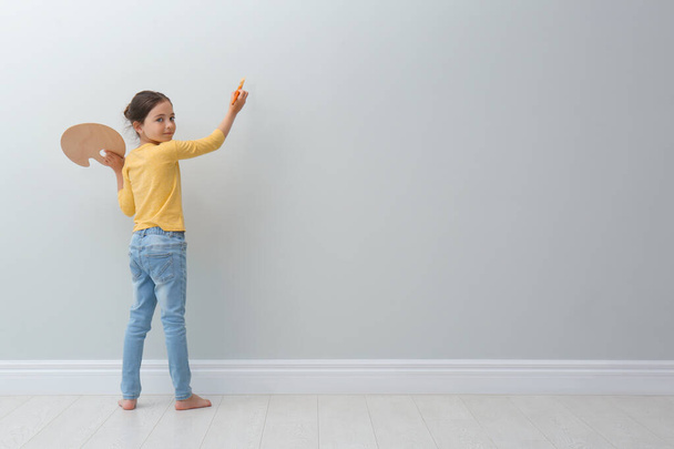 Little girl painting on light grey wall indoors. Space for text - Fotó, kép