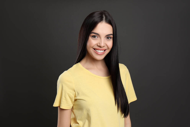 Portrait of happy young woman with beautiful black hair and charming smile on dark background - Zdjęcie, obraz