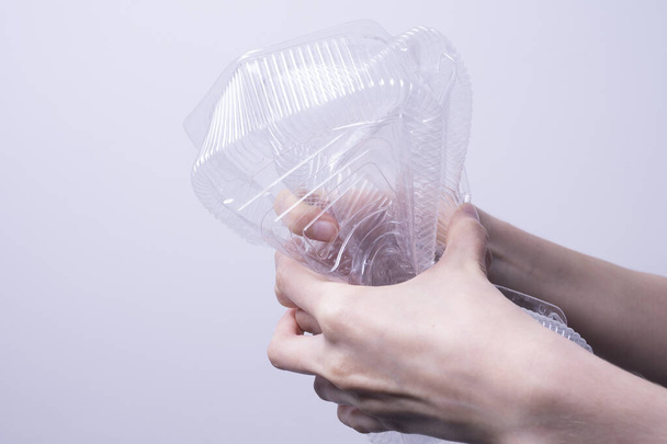 female hand holding transparent plastic packaging on gray background - Φωτογραφία, εικόνα