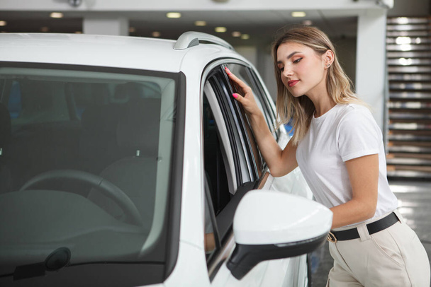 Houkutteleva naispuolinen asiakas etsii sisällä uusi auto myytävänä autoliikkeessä, kopioi tilaa - Valokuva, kuva