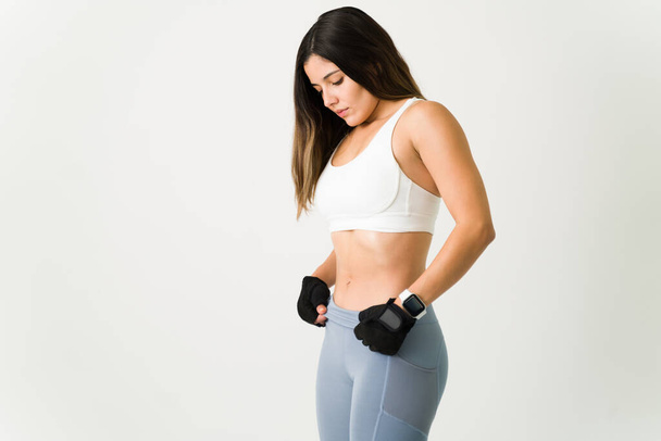 Fitness femme de formation pour avoir un ventre fort et montrant son noyau tonique. Jeune athlète avec des vêtements de sport travaillant sur ses abdos - Photo, image