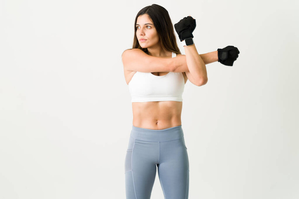 Sportliche Frau im Fitnessstudio. Schöne junge Frau in Aktivkleidung wärmt und dehnt ihren Körper vor ihrer Übung - Foto, Bild