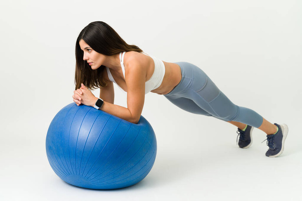 Mein Idealgewicht durch Bewegung zu halten. Fit und gesund macht die junge Frau während ihres täglichen Workouts ein Brett auf einem Stabilitätsball - Foto, Bild