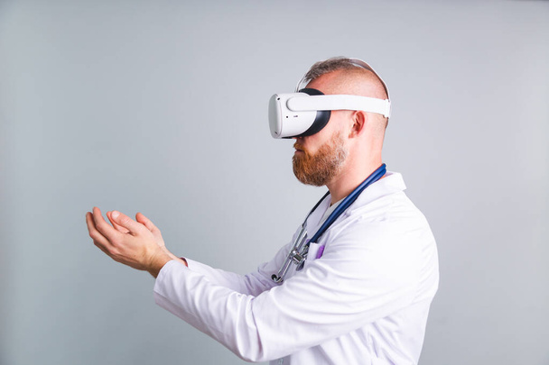 Guapo médico masculino sobre fondo gris en gafas de realidad virtual - Foto, imagen
