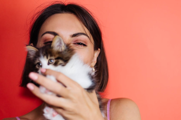 Leikkisä nainen punaisella taustalla pikku kissanpentu, lähellä muotokuva - Valokuva, kuva