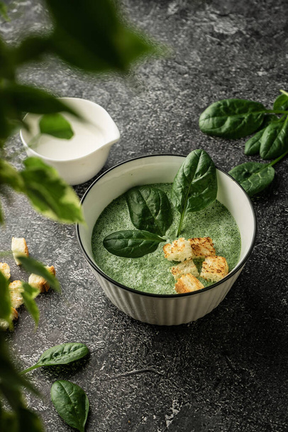 cream soup of green fresh spinach with cream and croutons for decoration. on a dark copyspace background, For menus and articles with recipes - Фото, изображение