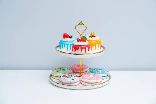 Kirkkaat ja värikkäät kakut ja donitsit asetetaan kaksiportaiselle lautaselle. Teeaika värikkäitä hedelmiä kakku - Valokuva, kuva