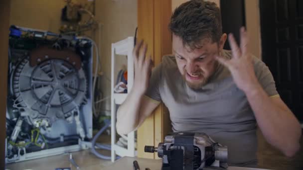 Чоловік розсердиться, коли виправляє пральну машинку вдома
 - Кадри, відео