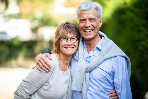 Portrait heureux couple d'âge mûr dans les bras de l'autre à l'extérieur dans le parc - Photo, image