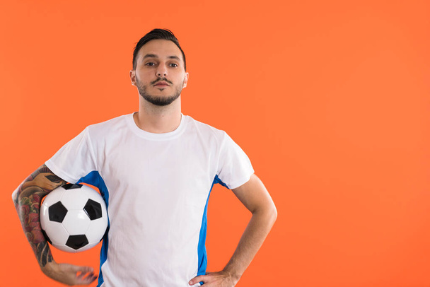 Poważny wygląd Piłkarz izolowany na pomarańczowym tle - Zdjęcie, obraz