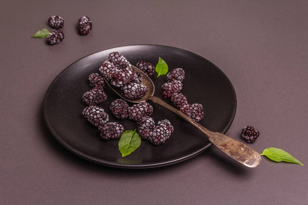 Karhunvatukoita keraamisella lautasella. Jäädytetyt hedelmät terveelliseen ruokavalioon. Minimalistinen konsepti, musta kivi betoni tausta, kova valo, tumma varjo, tasainen - Valokuva, kuva