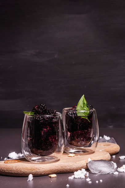 Een verfrissende frambozenfruitdrank. Koude zomerbessencocktail, modern hard licht, donkere schaduw. Zwarte steen beton achtergrond, kopieer ruimte - Foto, afbeelding