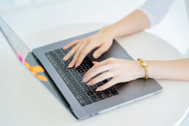 Mains d'une femme opérant un ordinateur portable dans une pièce lumineuse - Photo, image