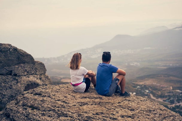 Couple sits on a rock, looking at the landscape and enjoying the view and fresh air. - Photo, Image