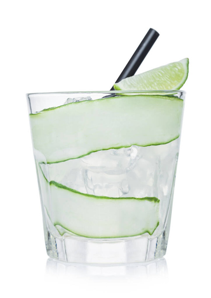 Gimlet cocktail in glass with ice cubes and straw, cucumber and lime slice on white background.  - Fotó, kép
