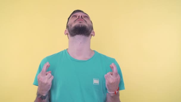 Een portret van een jonge man met gekruiste vingers en gesloten ogen biddend - Video