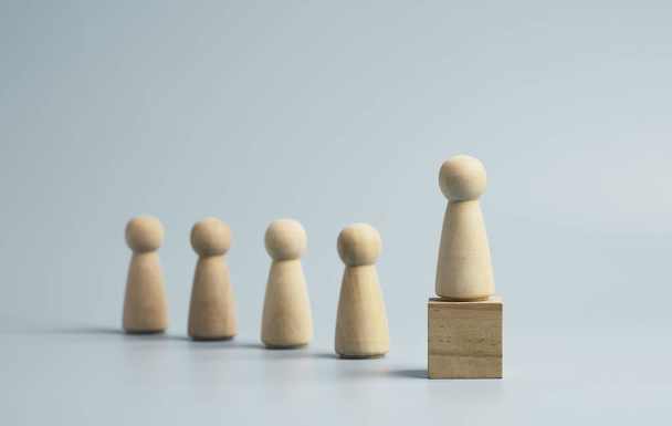 Houten figuur op houten kubus blok op blauwe achtergrond, promotie tot leiderschap en management groeiconcept. - Foto, afbeelding
