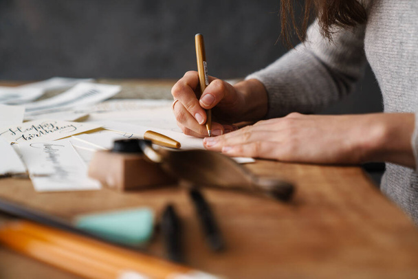 Calligrapher girl writing while working at table indoors - Valokuva, kuva
