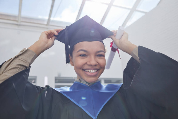 Low angle portrait of African-American young woman wearing graduation hat and smiling at camera in sunlight - Foto, Imagem