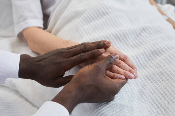 病院で彼の患者の手を握っているアフリカの医師のクローズアップ - 写真・画像