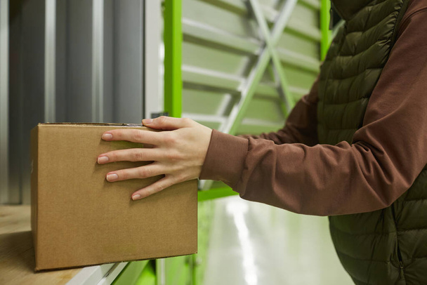 Close-up of woman holding cardboard box and shipping in in storage - 写真・画像