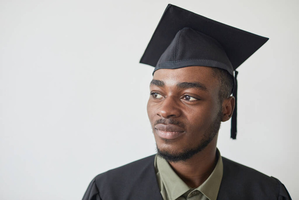 自信に満ちたアフリカ系アメリカ人男性の頭と肩の肖像白に対して卒業帽子をかぶって - 写真・画像