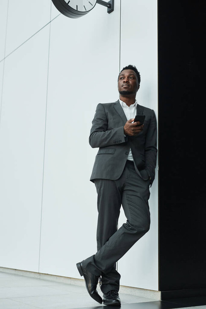 Grafický celovečerní portrét sebevědomého afroamerického podnikatele, který se dívá stranou, zatímco stojí v kancelářské hale, kopírovací prostor - Fotografie, Obrázek