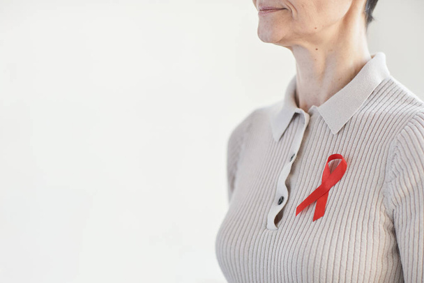 Detailní záběr zralá žena nosí červenou stuhu, zatímco stojí na bílém pozadí - Fotografie, Obrázek