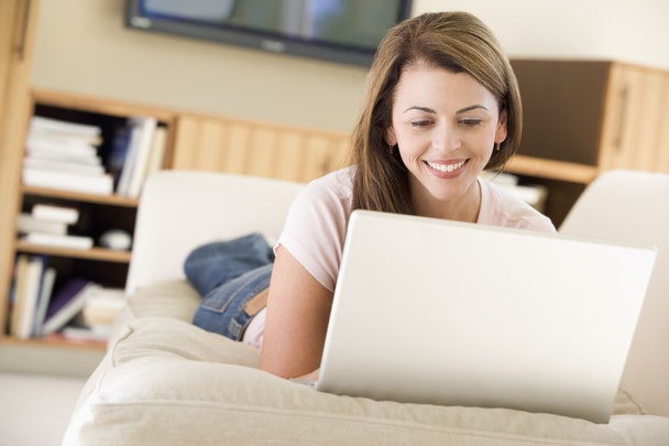Woman in living room using laptop smiling - Photo, Image