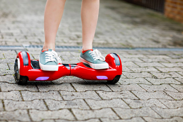 Close-up of kid boy on hover board. Child driving modern balance hoverboard. Excercise and sports for children, outdoor activity for young kids. - 写真・画像